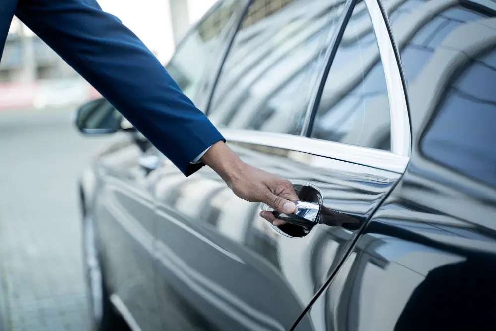 Chauffeur privé Rubycab en costume ouvrant la portière arrière d'une berline noire